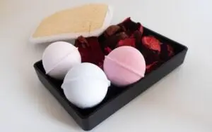 Blog Articles Close-up of pastel bath bombs with loofah and dried petals, perfect for spa ambiance.